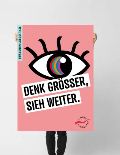 Person hält pinken Plakat mit buntem Augen-Motiv, Slogans ‚Denk größer, sieh weiter.‘ und Logo Schöne Aussichten auf hellem Hintergrund
